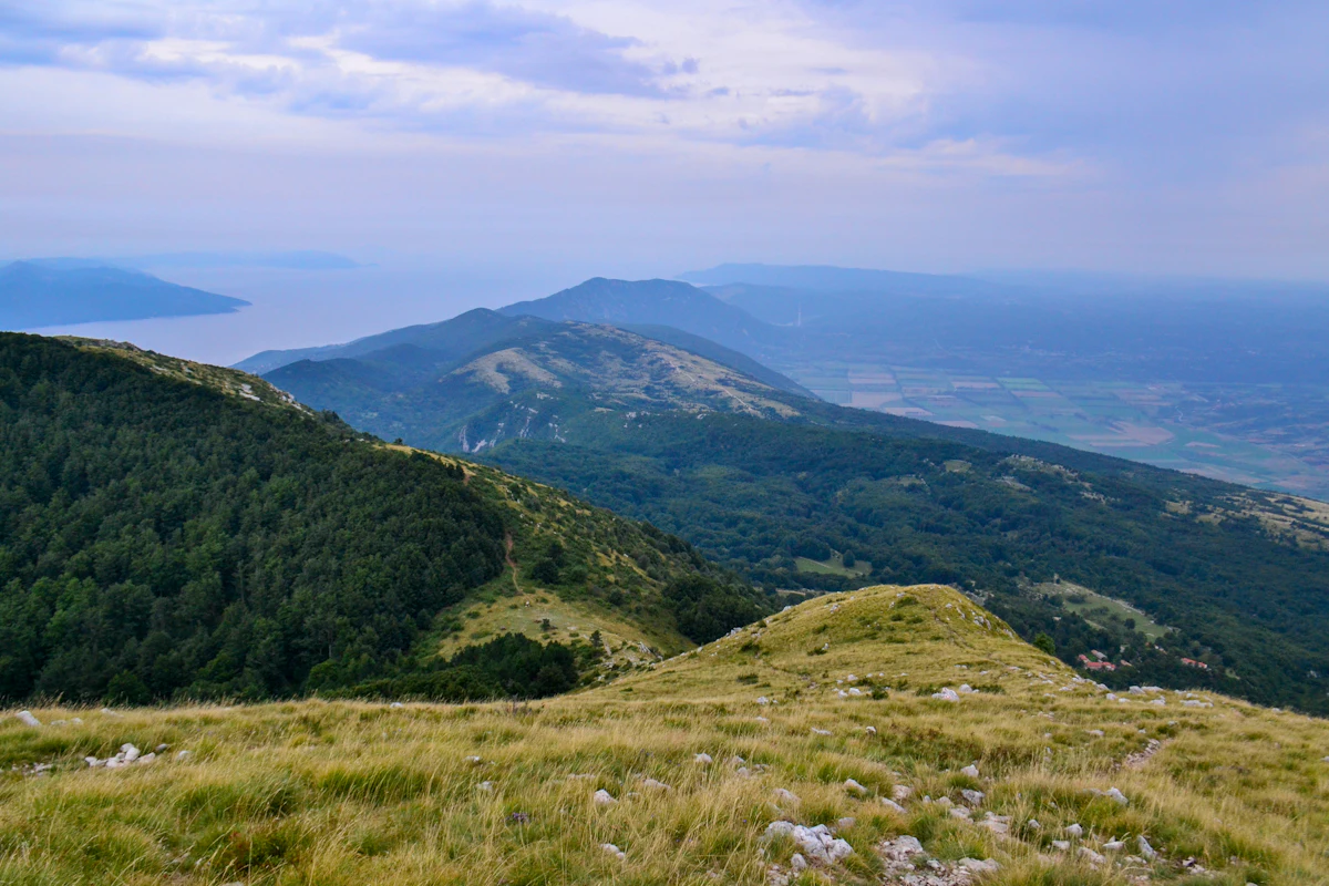 Grassy slopes near Vojak on Učka, looking down over forested ridges to the sea