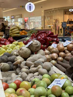 Fresh produce display featuring yams, plantains, and Scottish root vegetables side by side.