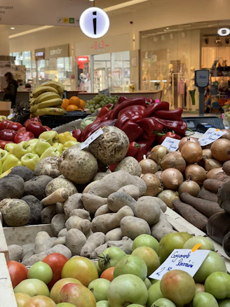 A vibrant display of fresh African yams, Scottish potatoes, and colorful spices arranged in woven baskets.