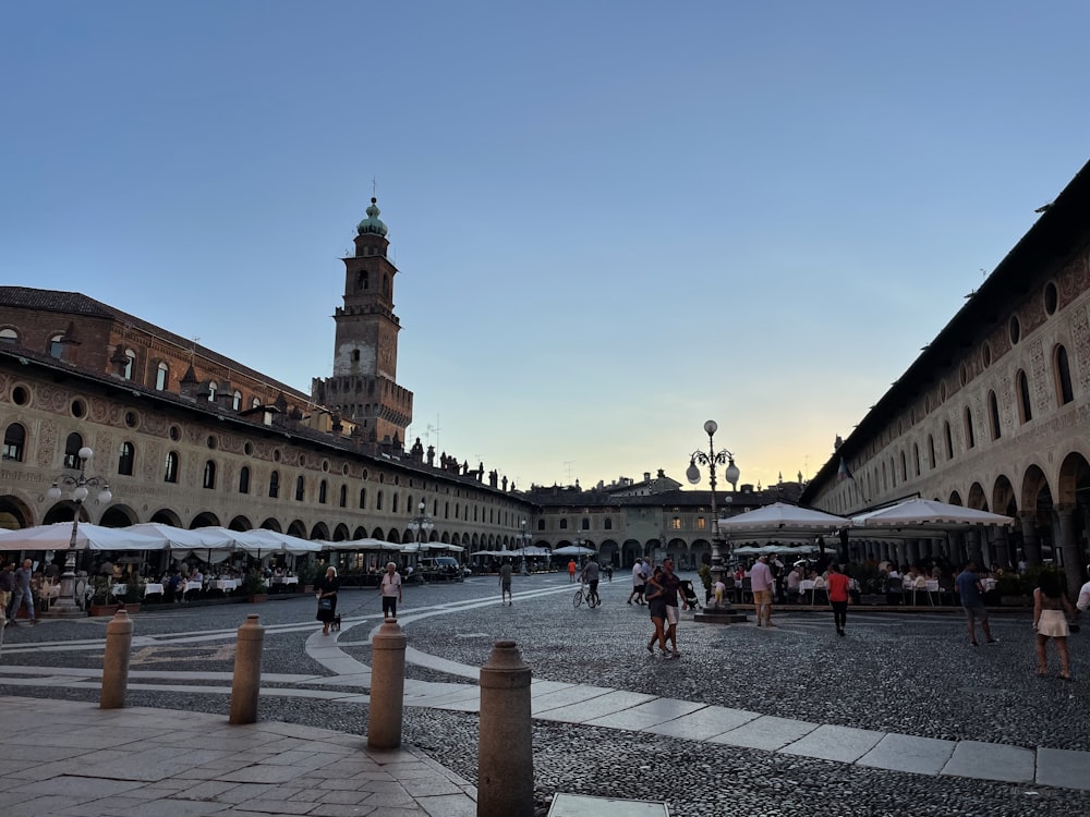 a group of people walking around a courtyard with buildings in the background