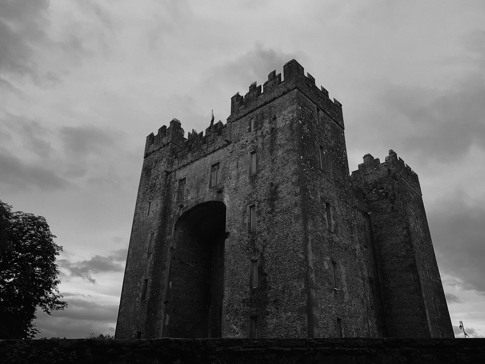 a stone building with a tree in the front with Bunratty Castle in the background