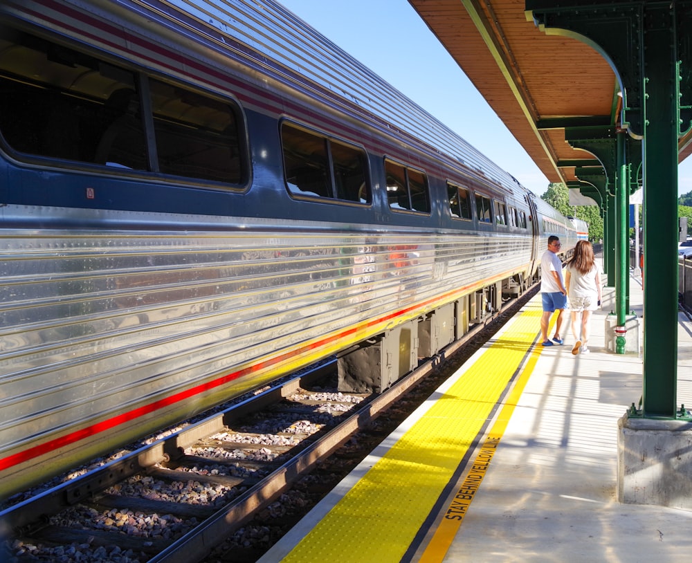 a couple of women walking on a platform next to a train