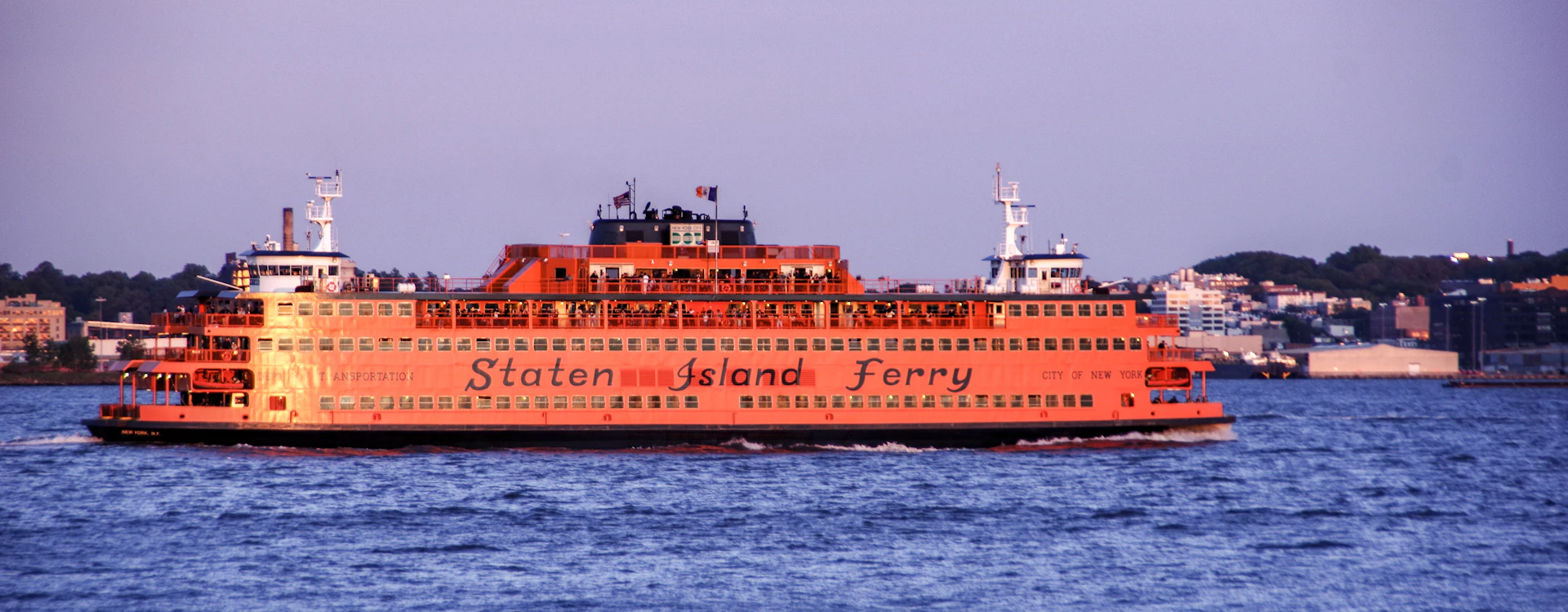 a large red ship with Staten Island Ferry in the background