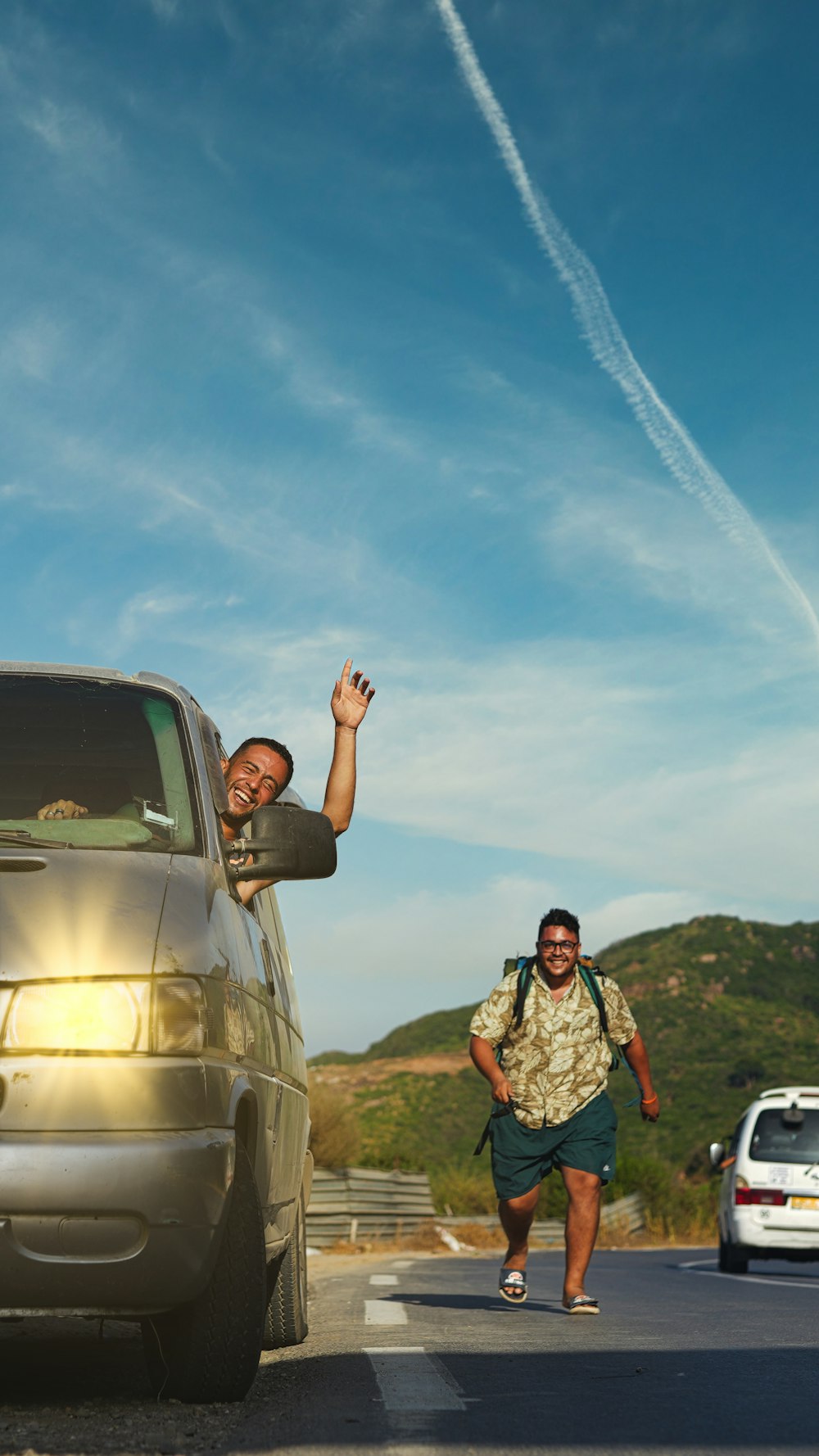 a man and a woman standing on a road with a car and a trail of smoke in the