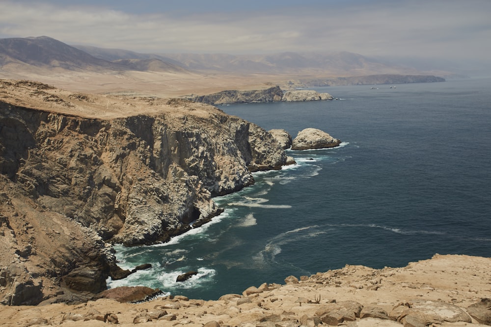 a rocky beach with a body of water in the background