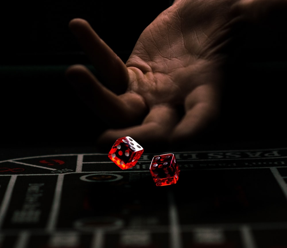 a hand with a finger pointing at a red and white dice