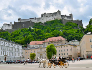 City square in Salzburg with horse and carriage in the foreground and Hihensalzburg Fortress behind