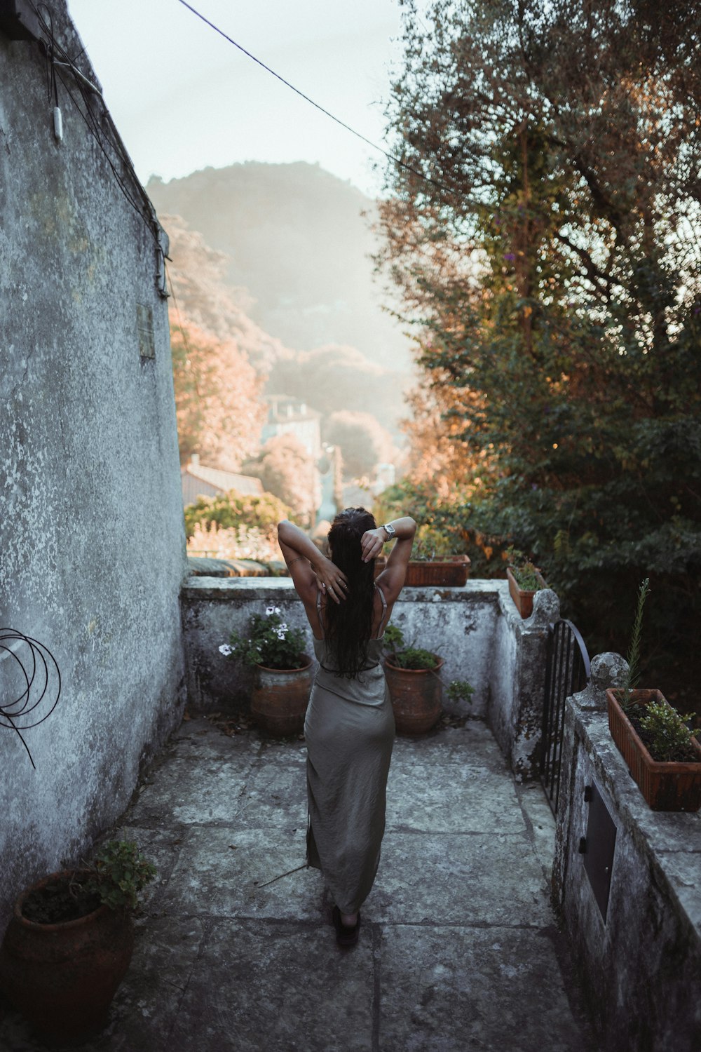 a person standing on a stone path with a tree and mountains in the background