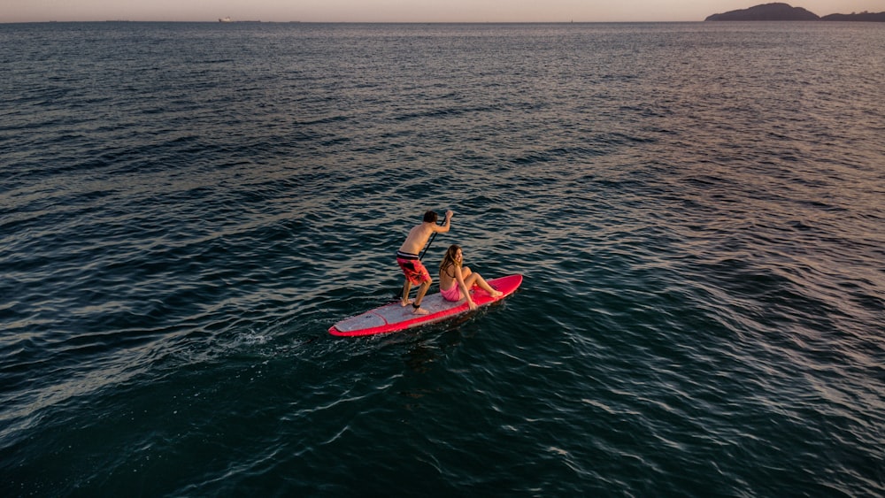 a man and a woman on a surfboard in the ocean