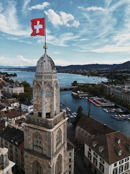 a large building with a flag on top and a body of water in the background