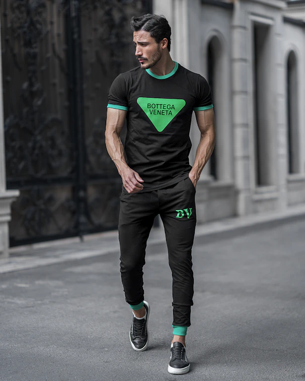 a man wearing a green shirt and black pants