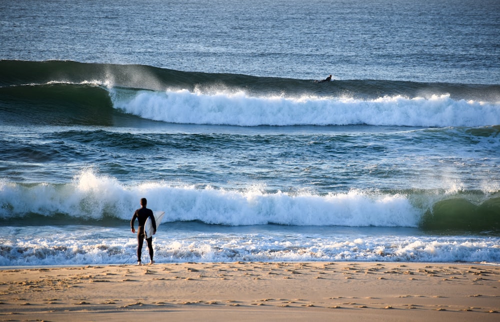 a person carrying a surfboard on a beach