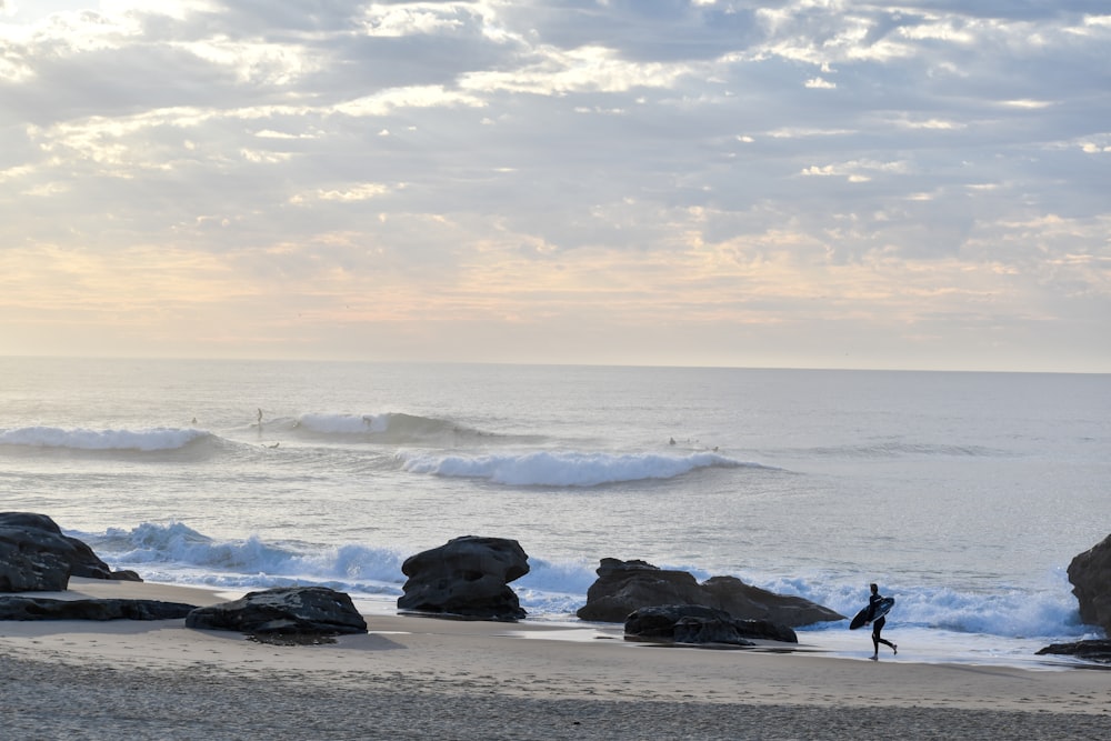 uma pessoa carregando uma prancha de surf em uma praia
