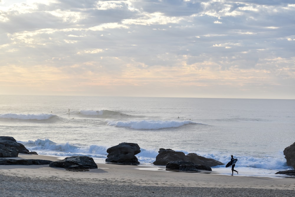 a person carrying a surfboard on a beach