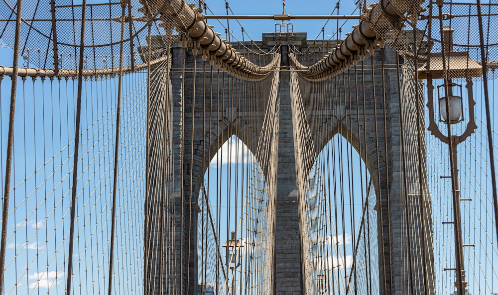 a tall bridge with cables with Brooklyn Bridge in the background