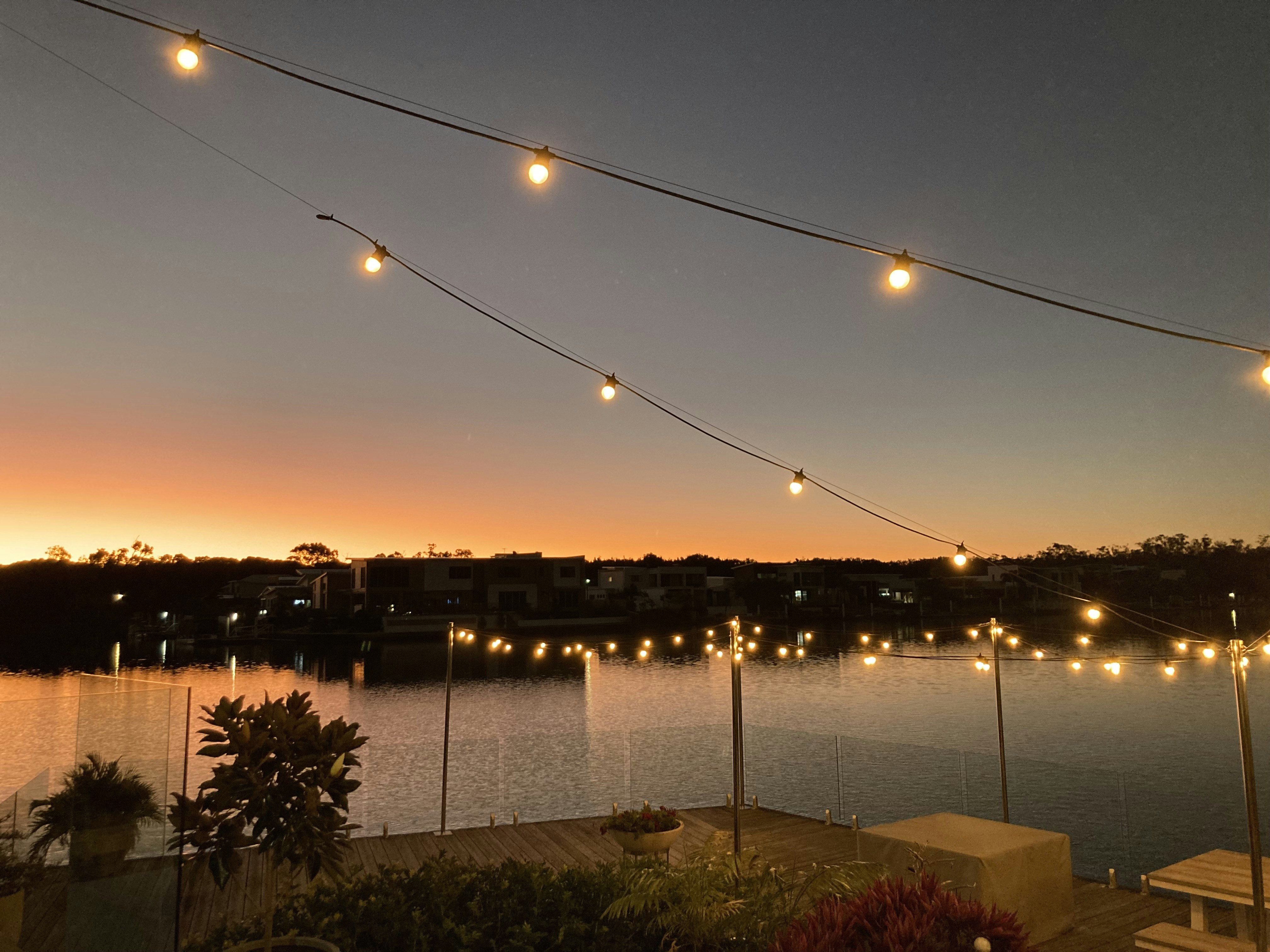 a body of water with a bridge and lights above it