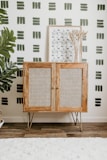 a wooden cabinet in front of a wall with a plant