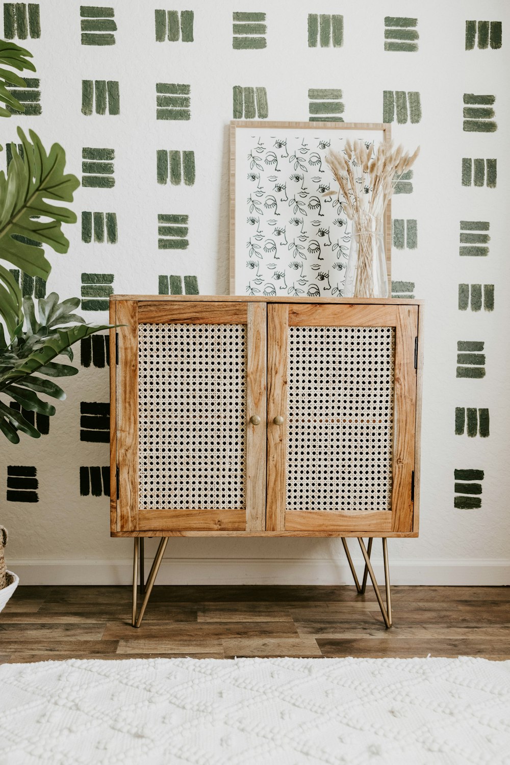 a wooden cabinet in front of a wall with a plant