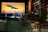 A nighttime urban scene featuring a large illuminated billboard showcasing an airplane with the text 'WORLD'S FASTEST AIRPLANES. BUILT IN ATL.' The background of the billboard depicts a city skyline at sunset. Nearby is a building with a vertical neon sign labeled 'PONCE.' The street below is moderately lit, with a car on the road and a sign reading 'EATS' on a wall.