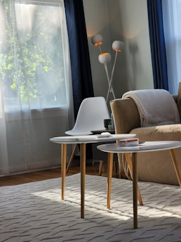 A serene minimalist living room corner with soft beige tones and a cozy throw blanket draped over a modern chair.