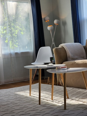 A cozy living room corner with a light linen sofa, textured throw blankets, and a small wooden coffee table.