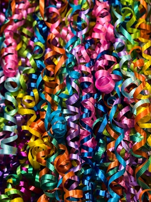 A multitude of colorful, glossy ribbons are entwined and curled, creating a festive and vibrant display.