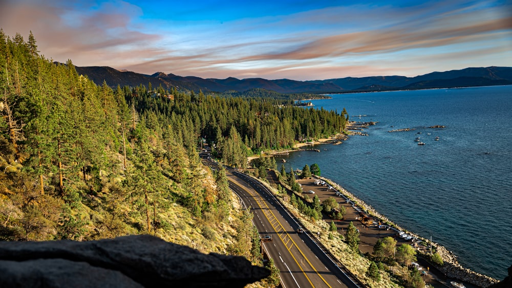 a road next to a body of water with trees on the side