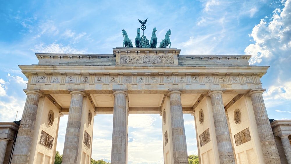 a large stone building with columns and statues on top with Brandenburg Gate in the background