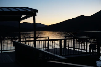 Outdoor deck with luxury timber railings overlooking tranquil lake waters at dusk.