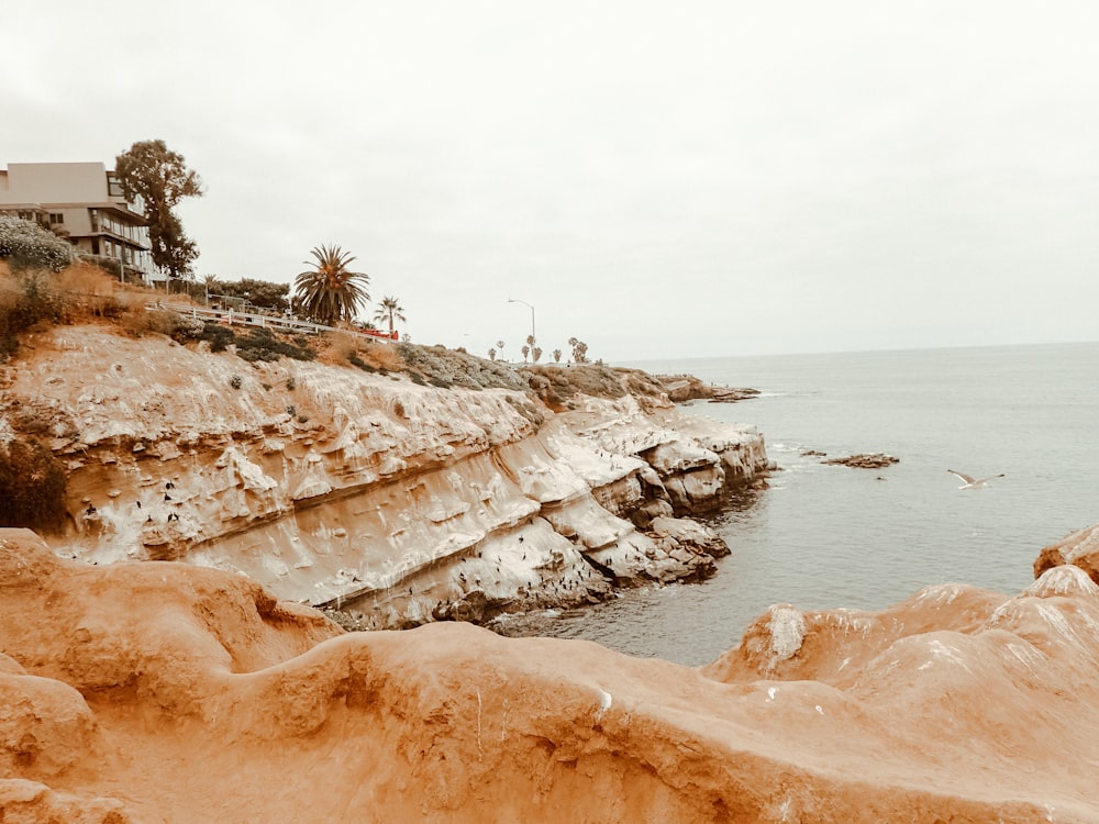 a rocky beach with a house on the shore