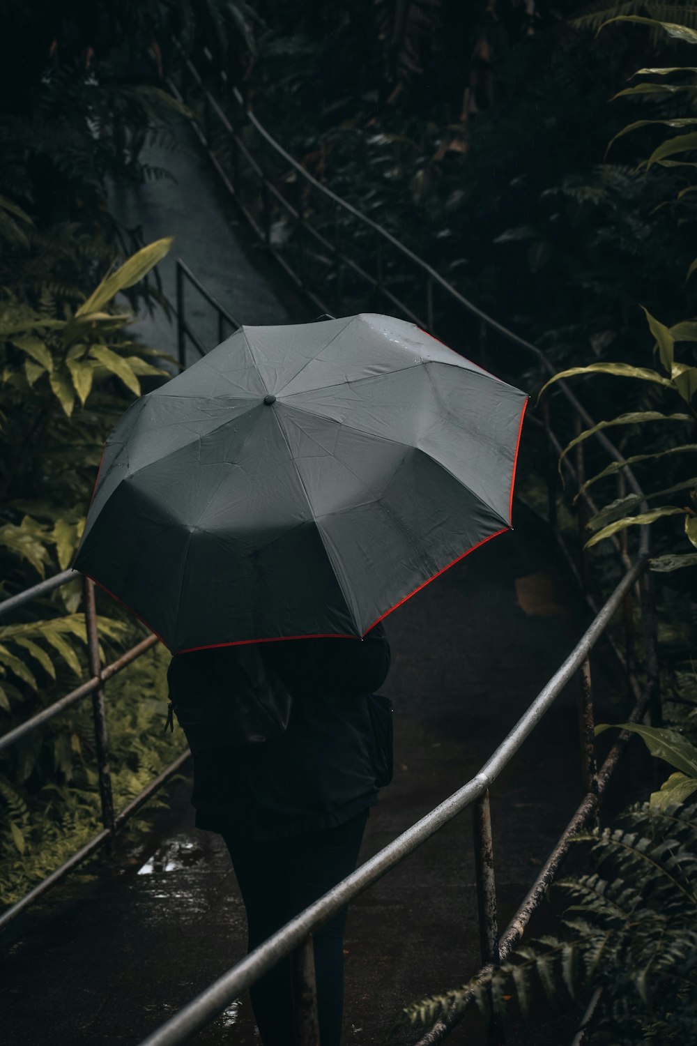 a person walking down a bridge with an umbrella