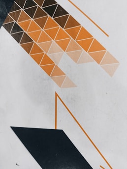 A geometric pattern consisting of rows of triangles in shades of brown and orange, arranged in a diagonal fashion on a light gray background. Darker triangles at the top gradually transition to lighter shades, with bold black and orange lines accentuating the design.