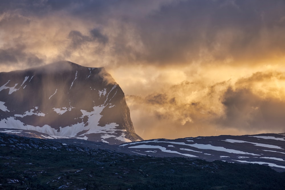 a snowy mountain with a cloudy sky