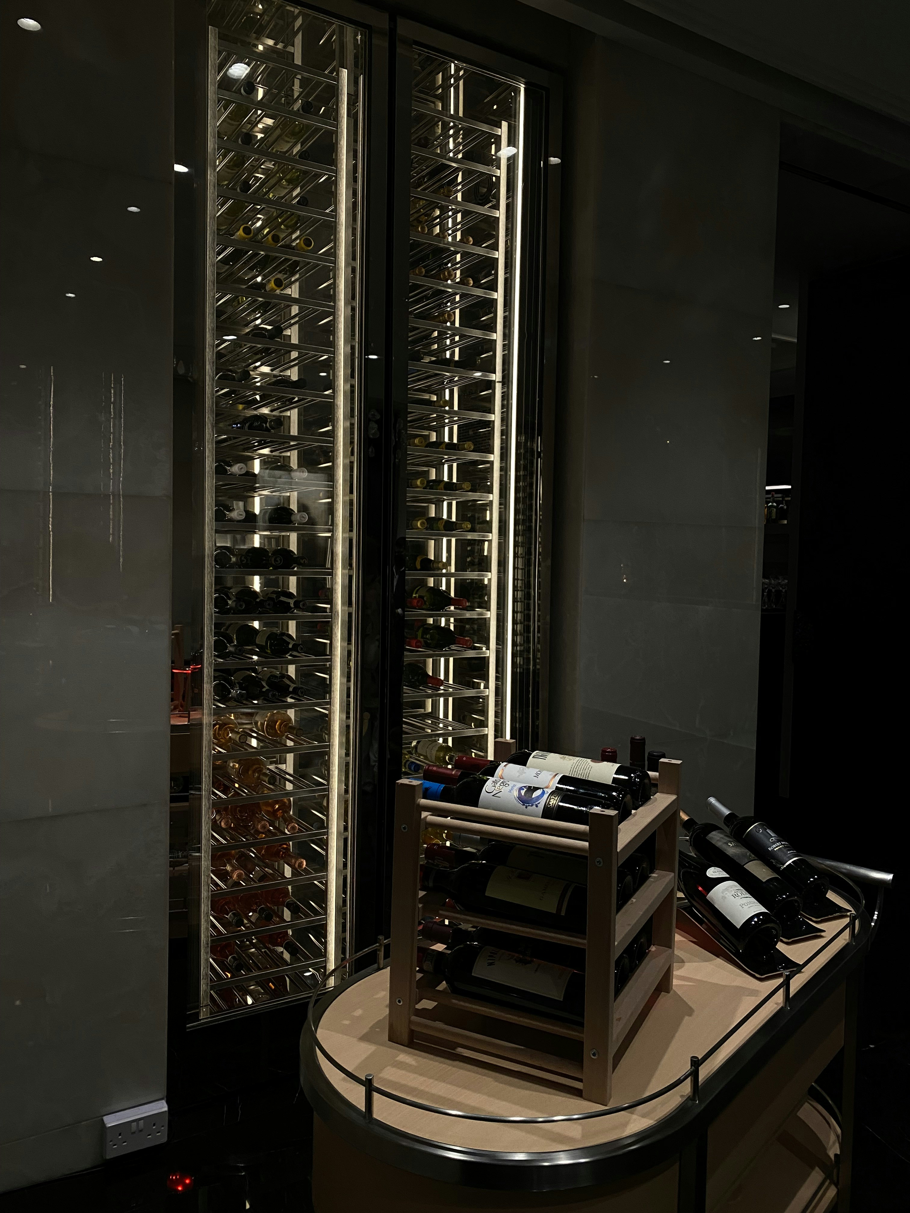 Wine cellar section of the dining car with curated bottles in mahogany racks, soft amber lighting, and velvet curtains