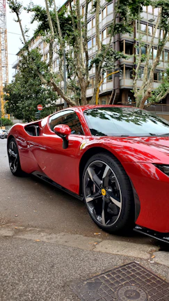 A vibrant red sports car with glossy vinyl wrap parked on a scenic GTA street.