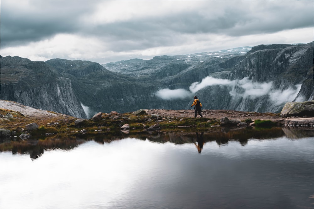 a person standing on a rock in front of a lake with mountains in the background