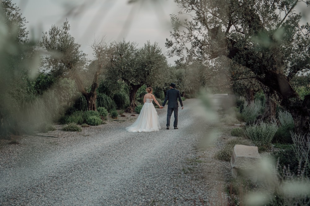 a man and woman walking down a path with trees on either side