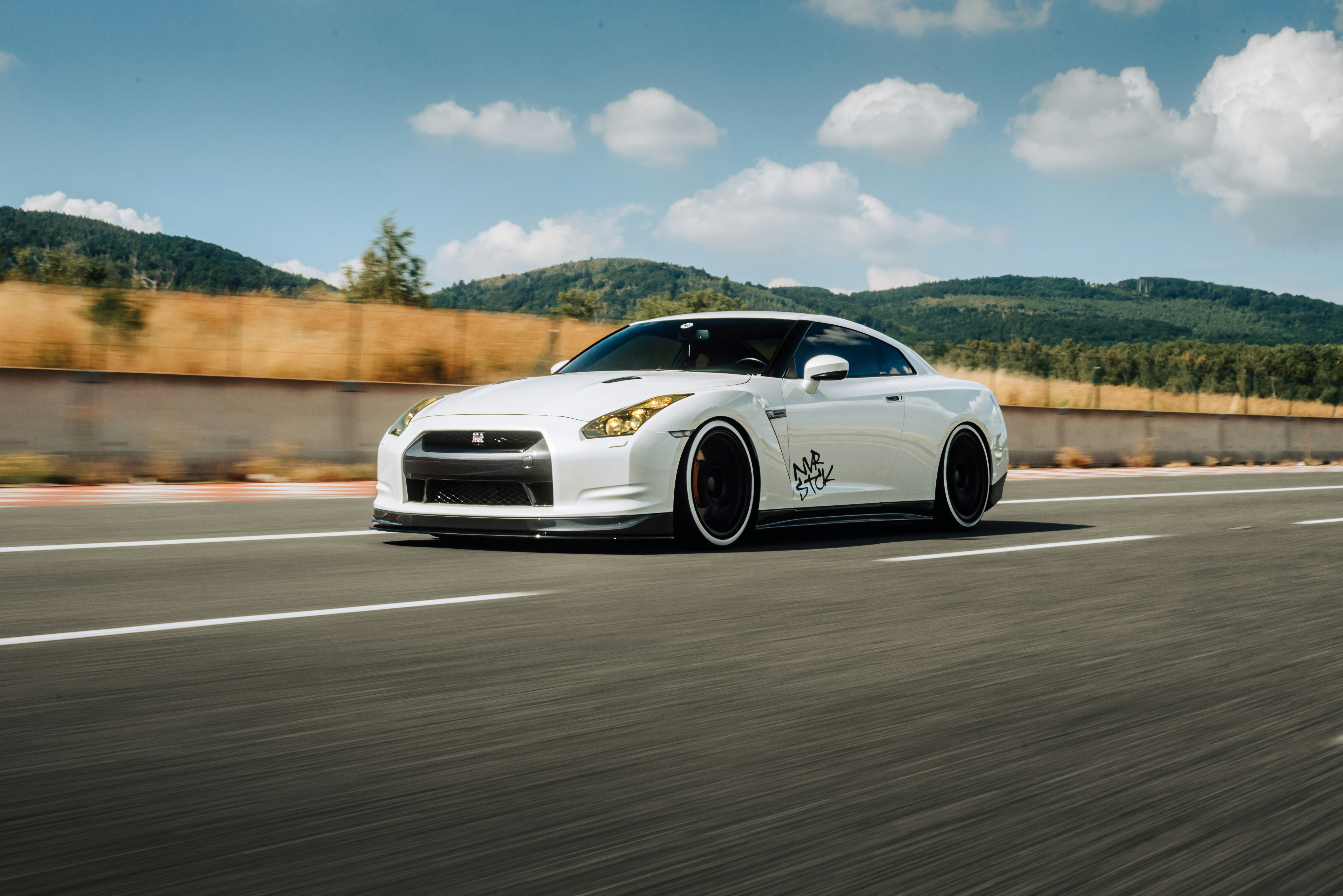 a white sports car driving on a road