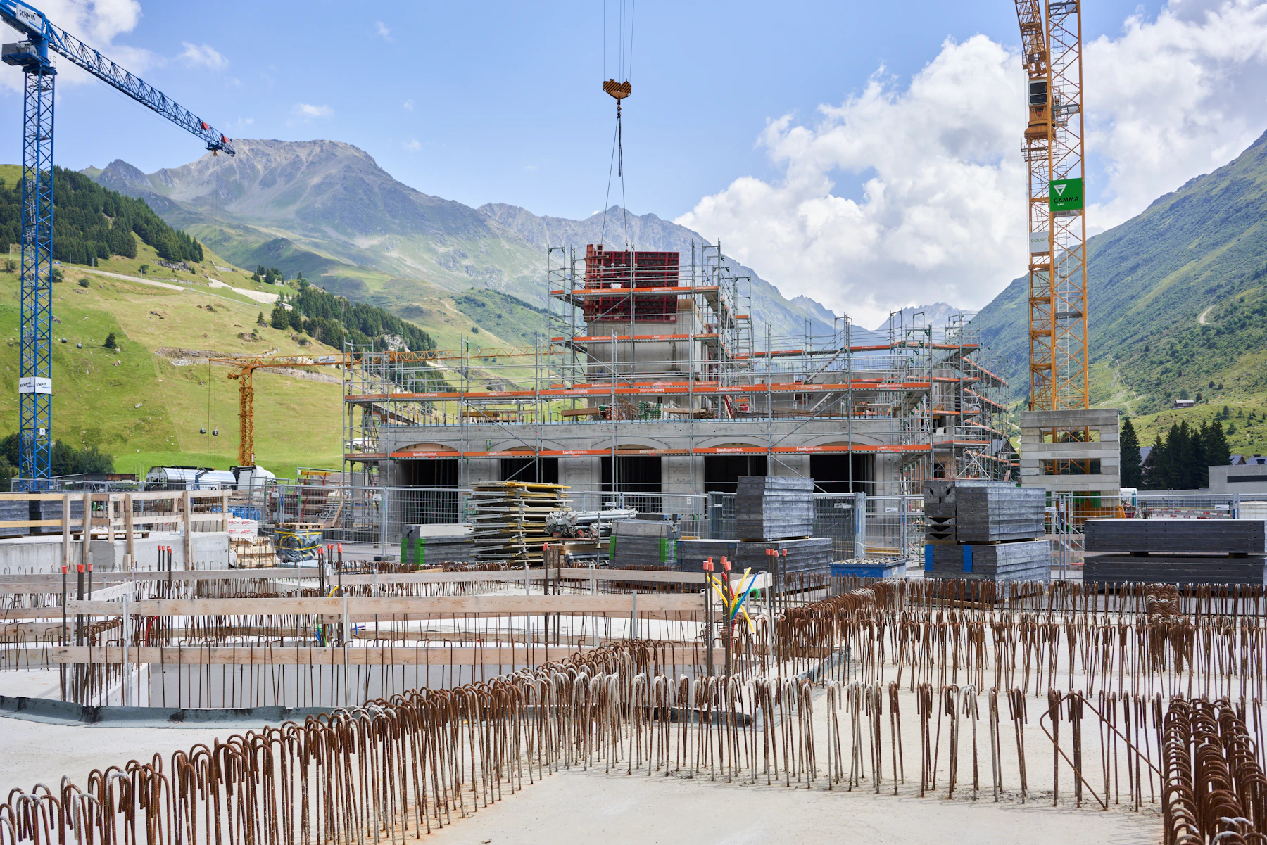 Baustelle mit Turmdrehkranen vor Schweizer Bergkulisse – Rohbau im Hochbau