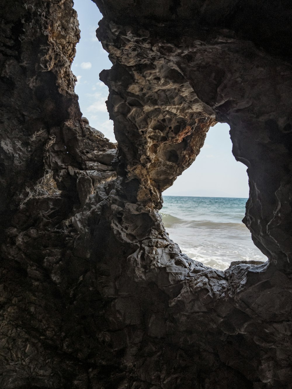 a view of the ocean through a rock cave