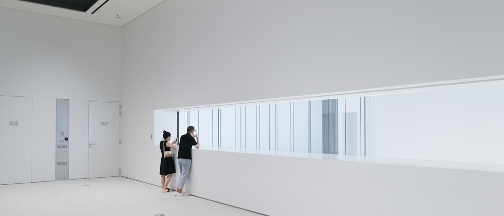 a man and woman standing in a room with white walls