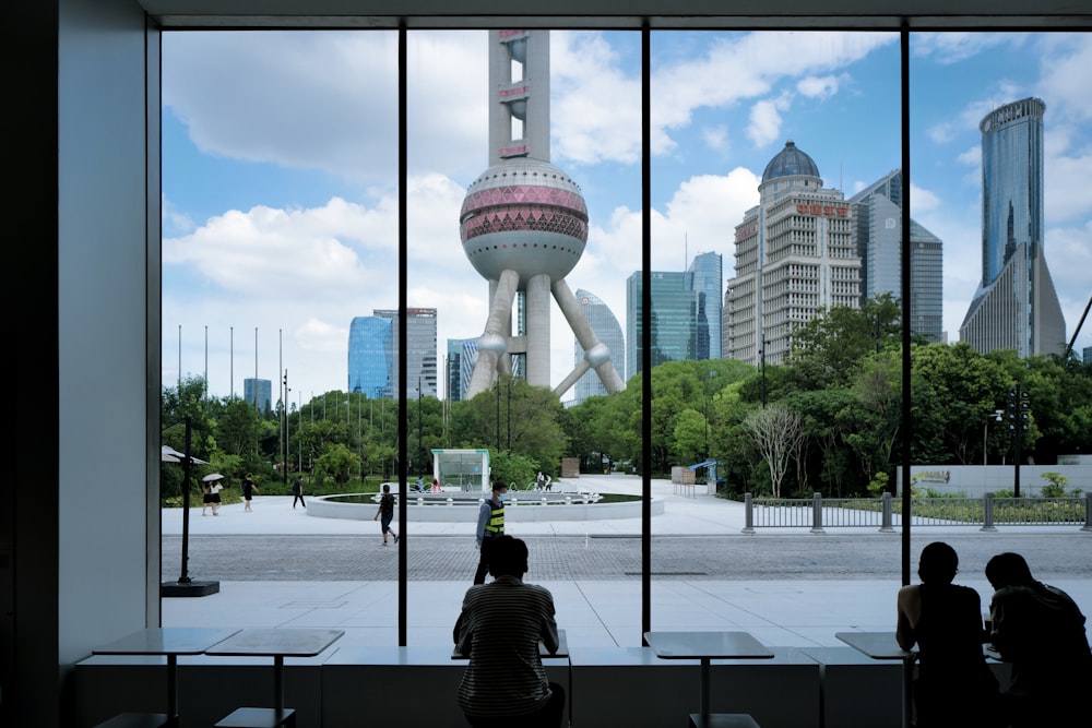 a group of people sitting in a park with a tall tower in the background