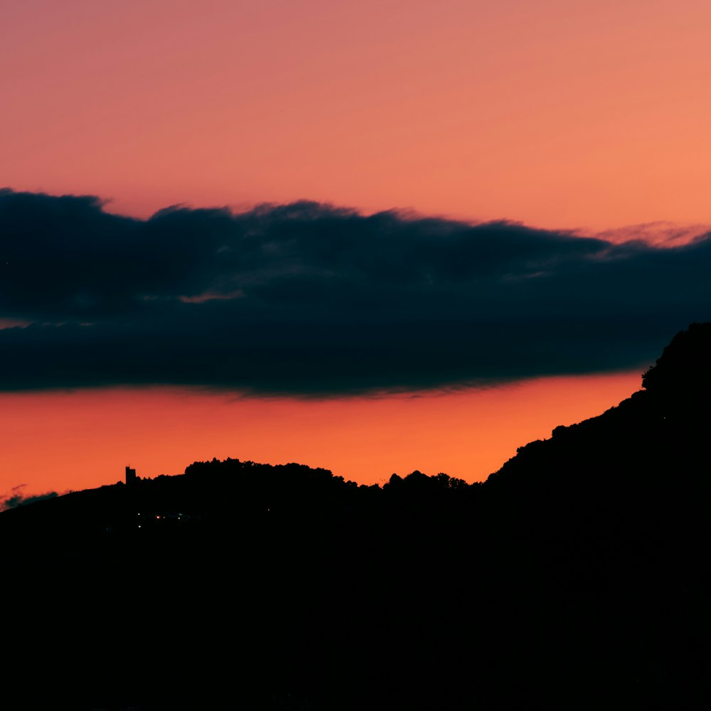 a silhouette of a hill and a sunset