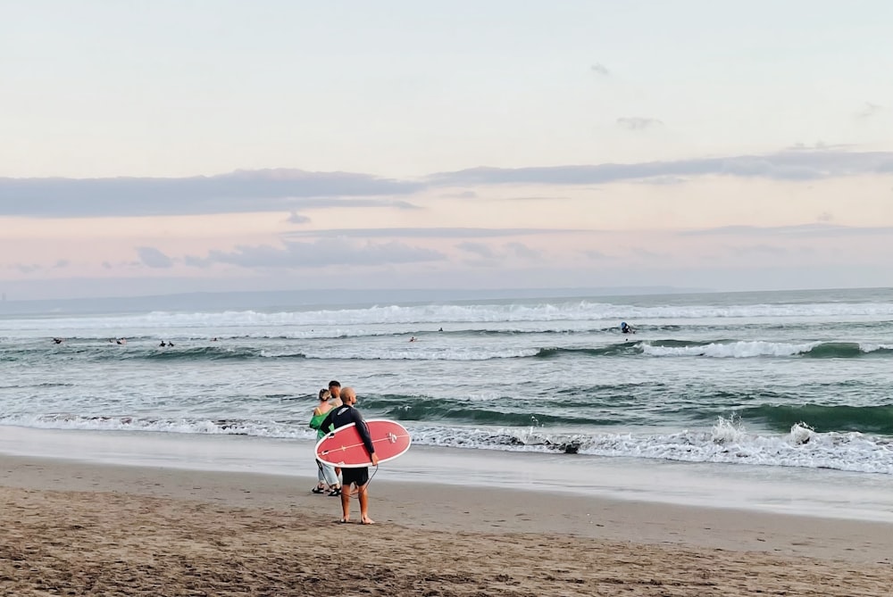 a couple of people walk on the beach carrying surfboards