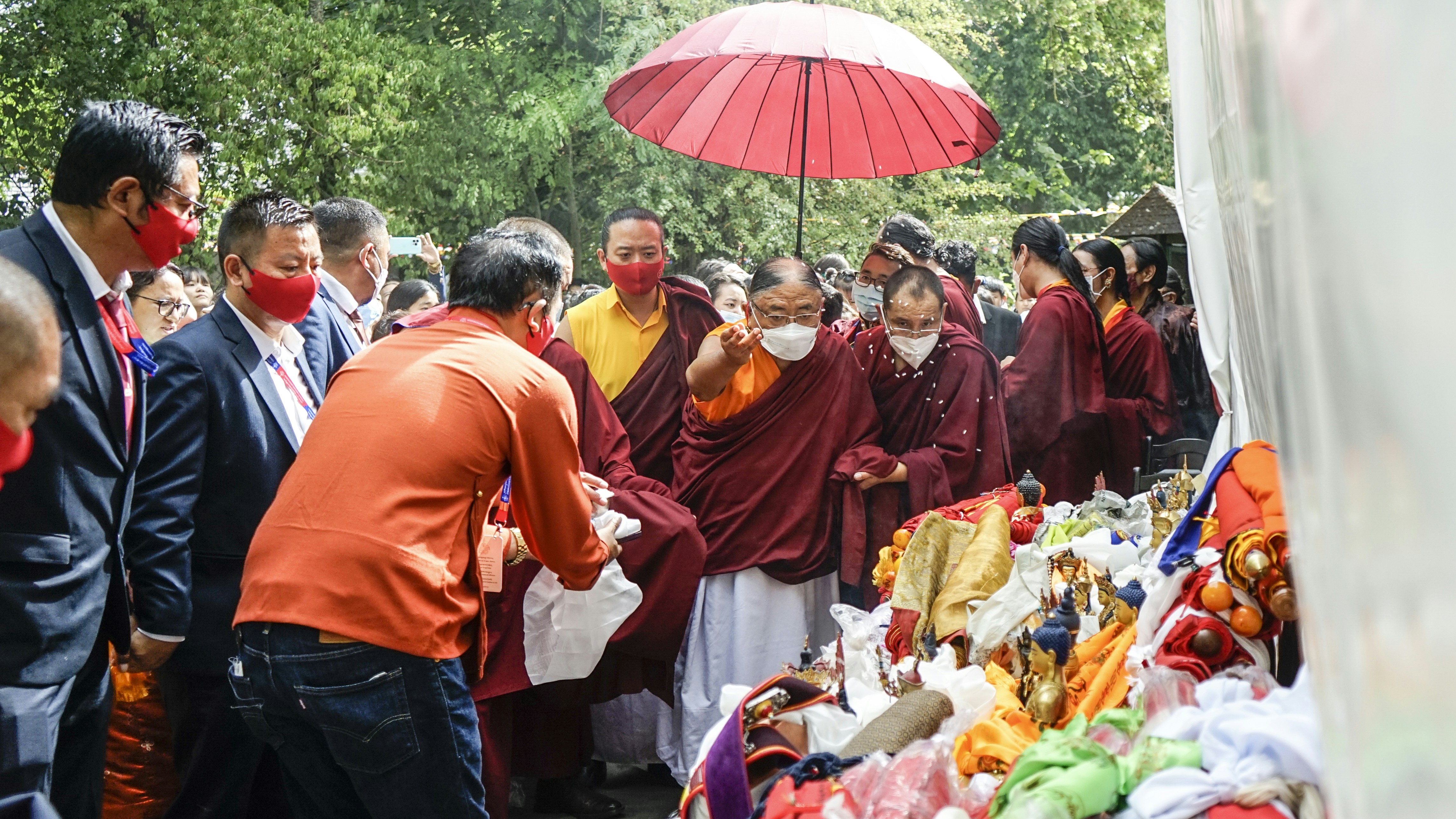 a group of people standing around a table with food and umbrella