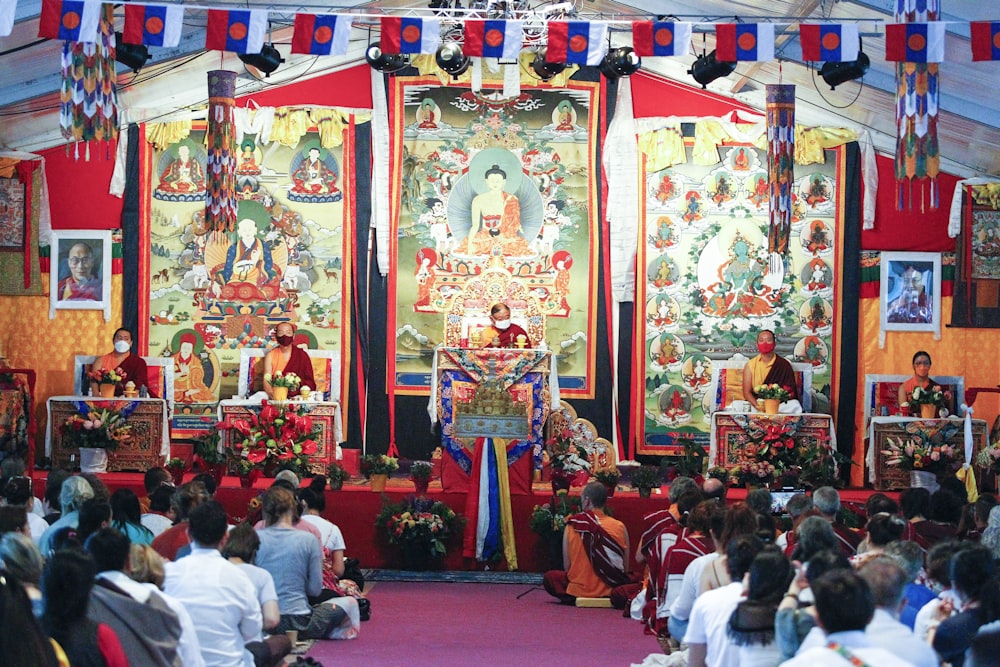 a group of people sitting in a room with a stage and a group of people in the front