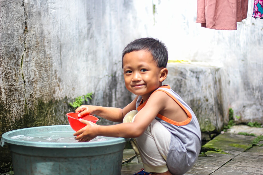 a young boy holding a red bucket