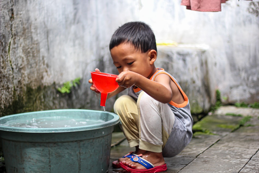 a young boy playing with a red bucket