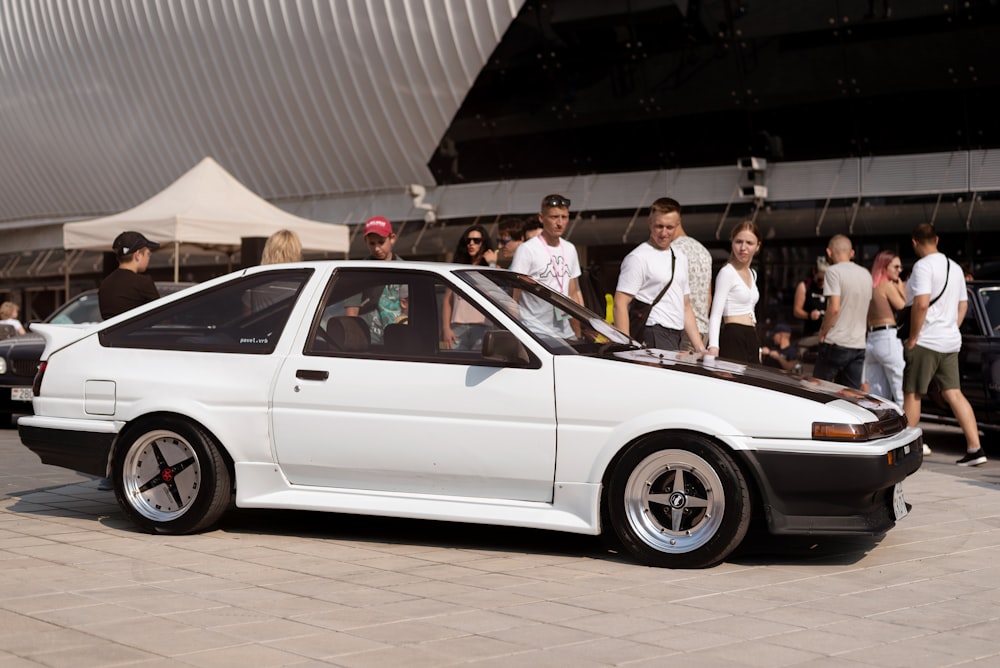 a group of people standing around a car