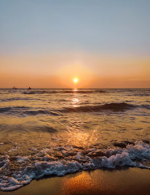 Sunset view over the sparkling ocean with guests kayaking near the shore.